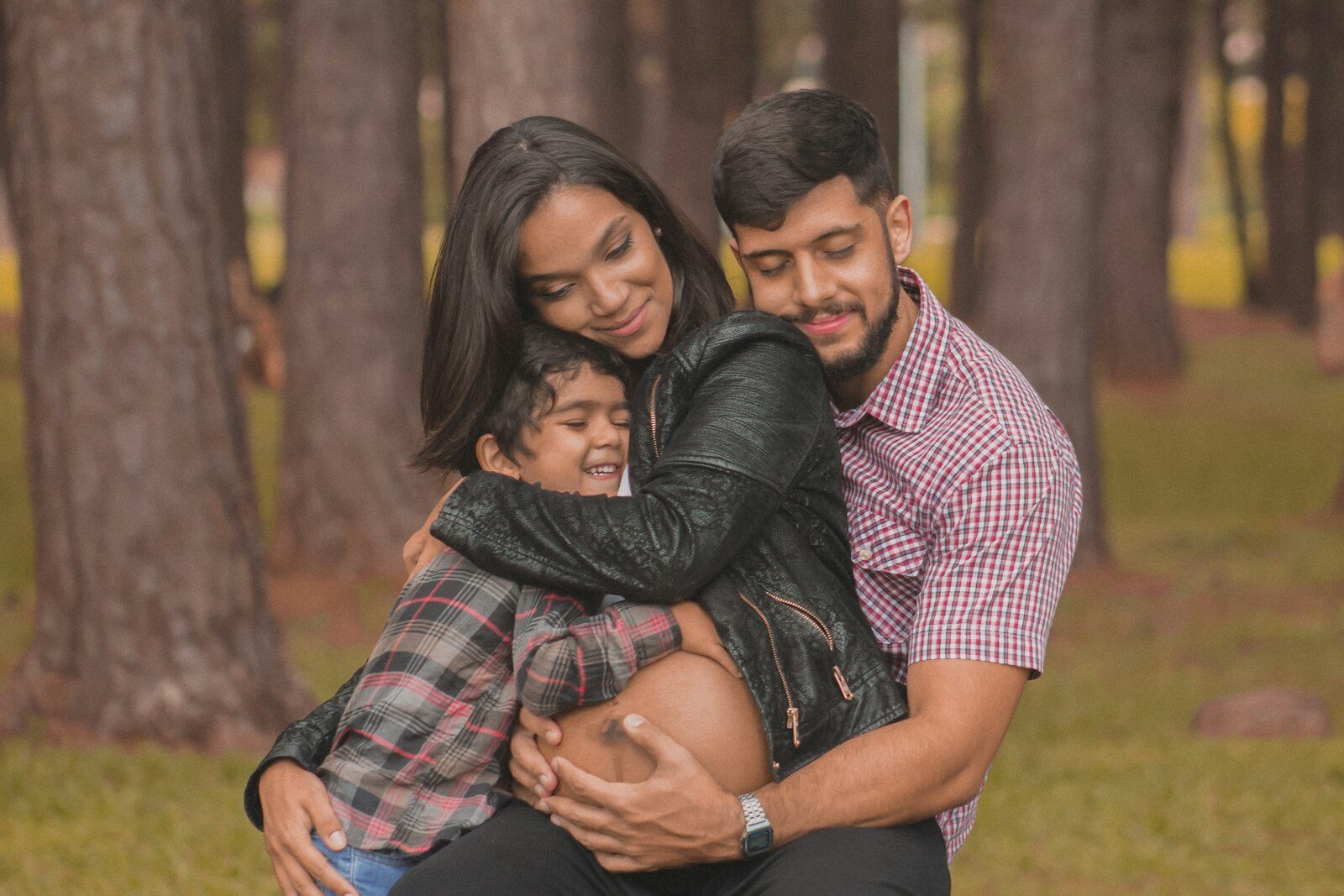 Casal abraçado ao filho pequeno em um bosque