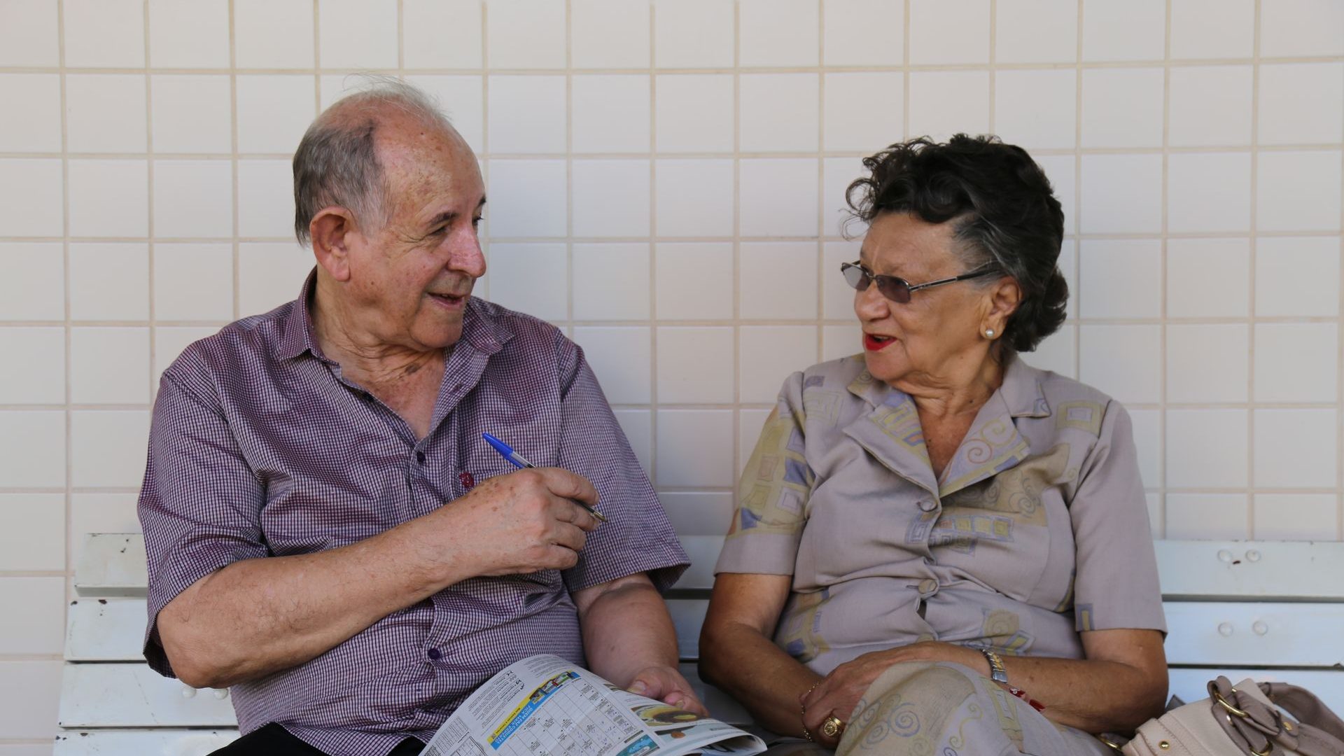 Casal idoso conversando em um banco, olhando um impresso juntos