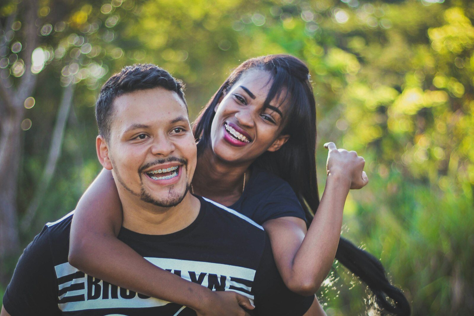Casal jovem sorrindo ao ar livre, abraçado