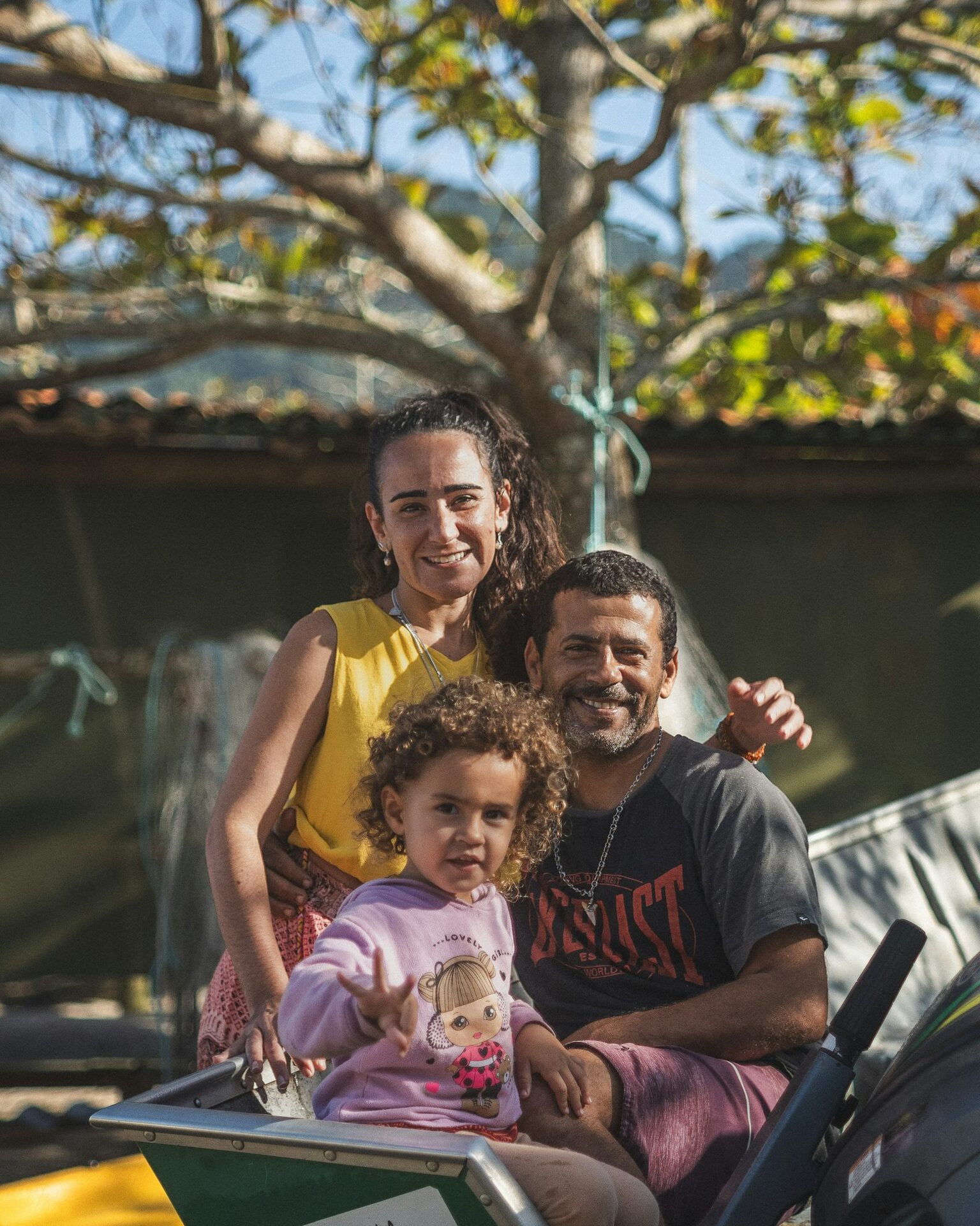 Casal com a filha pequena no colo, sorrindo no quintal de casa