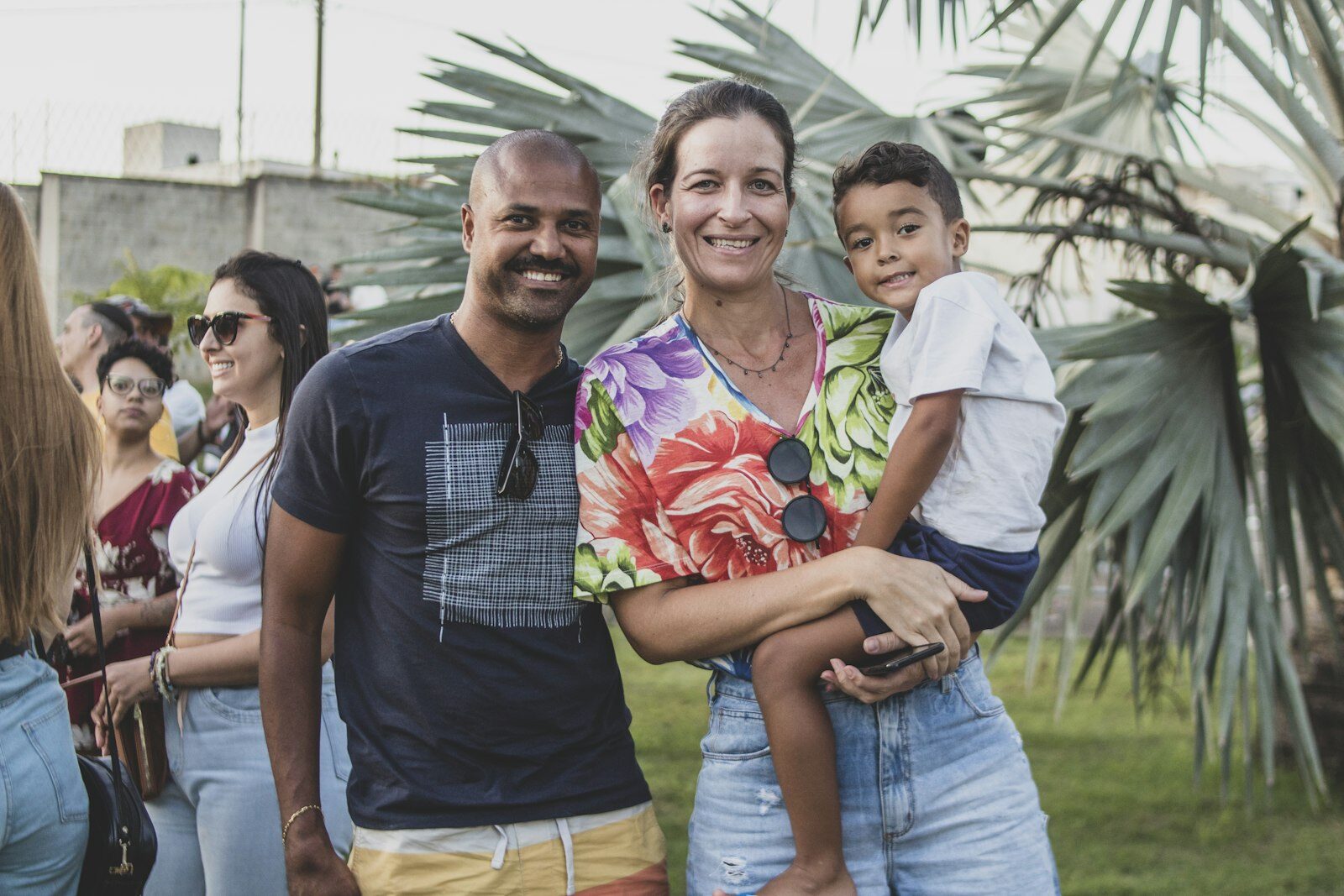 Casal sorrindo com o filho pequeno no colo, ao ar livre